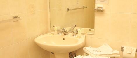 A bathroom with a sink, mirror, towel rack, and a small shelf with toiletries.