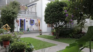 A courtyard with a white building, potted plants, and a small garden area. - Hotel Casa González (Mexico City)