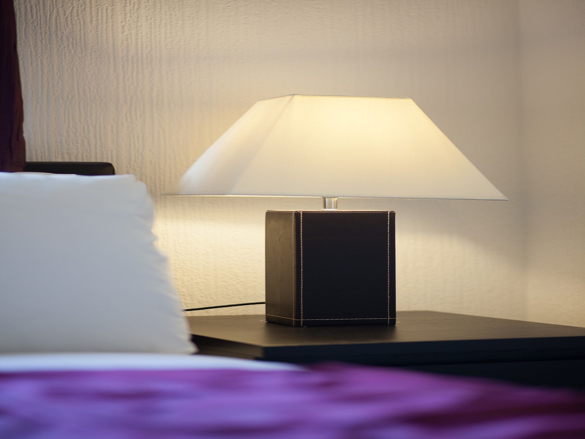 A bedside table with a lamp and a pillow.