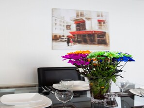 A dining table set with plates, cutlery, and a vase of colorful flowers. - Leith Apartments (Edinburgh)