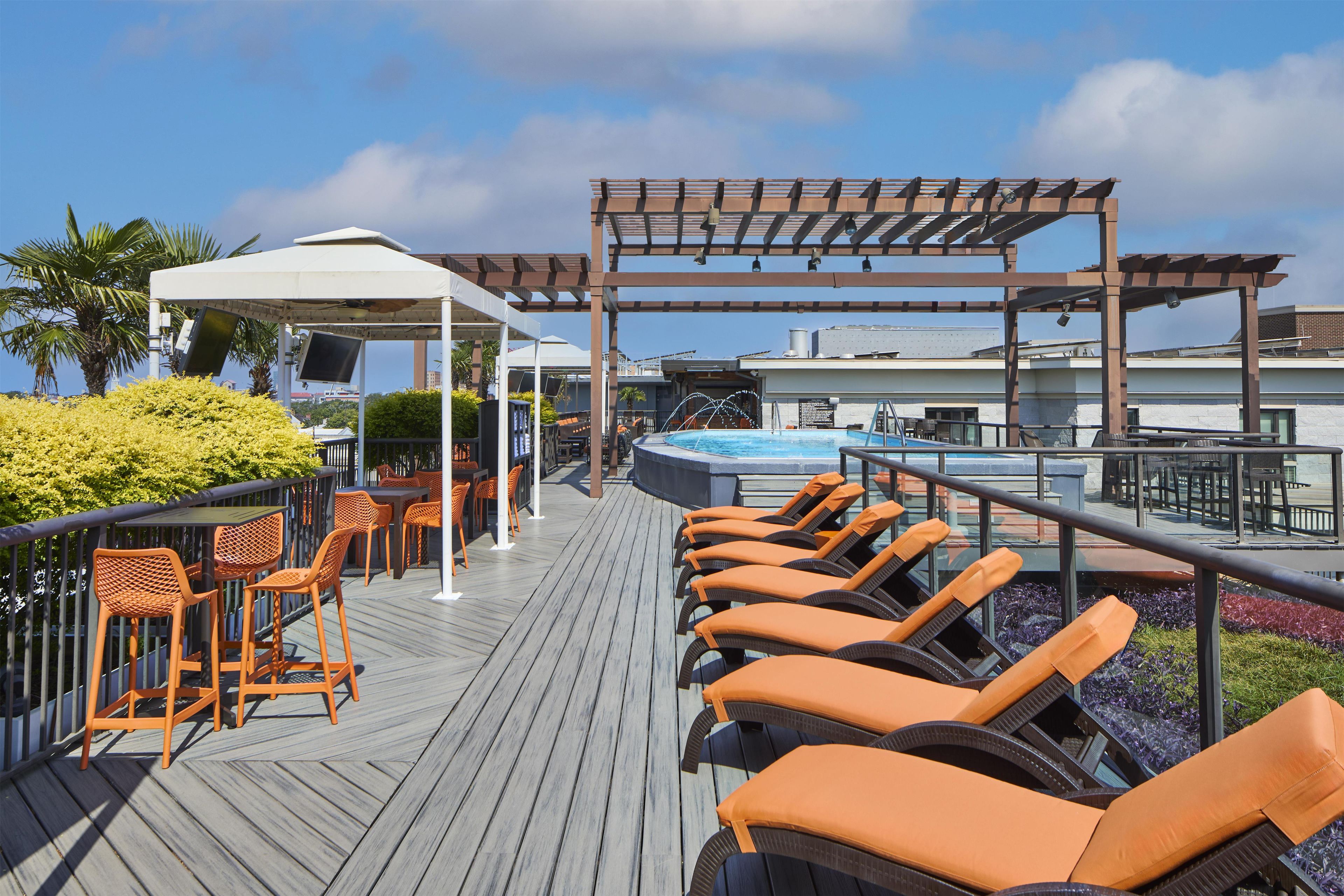 Een terras met loungebedden, een zwembad en een pergola.