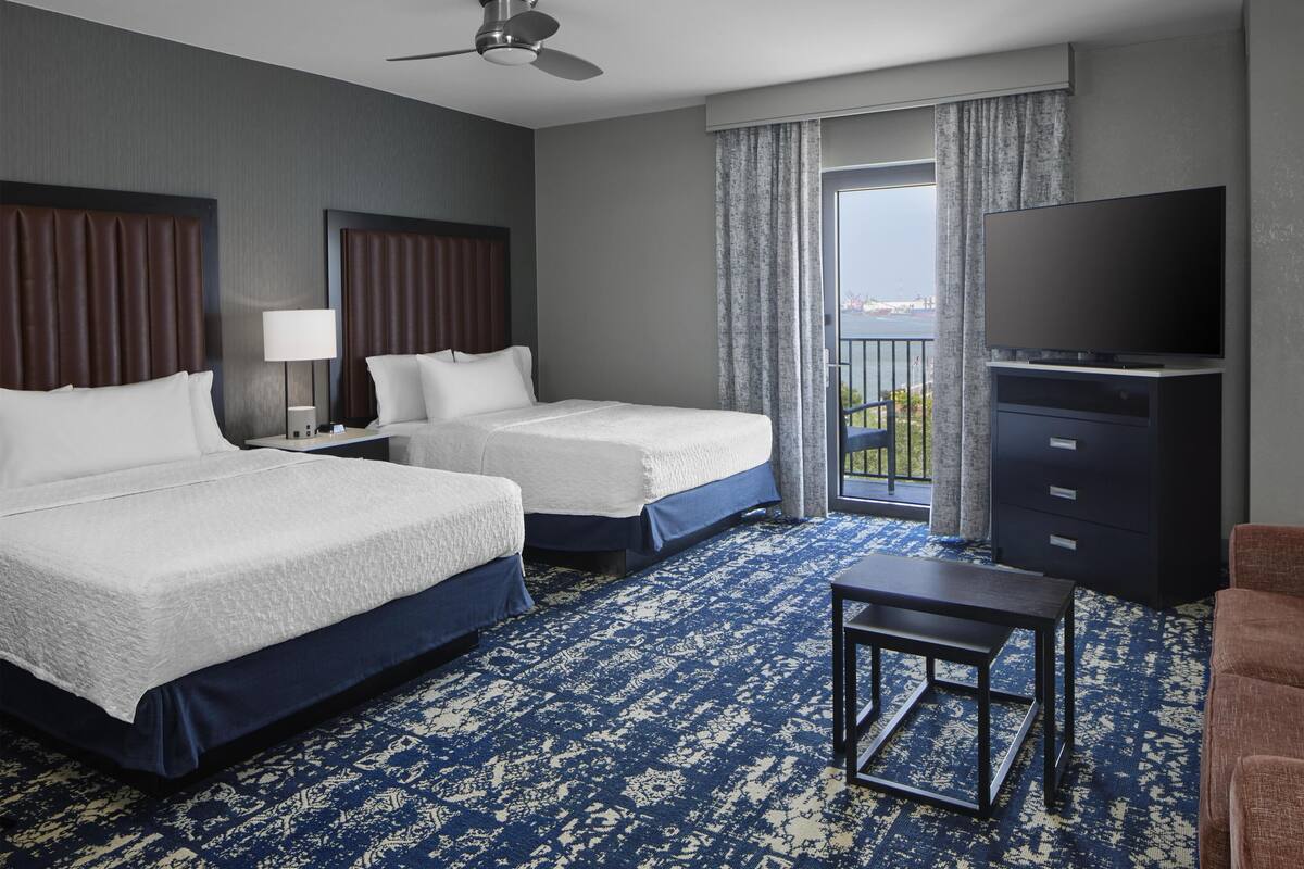Een hotelkamer met twee bedden, een televisie, een bureau en uitzicht op de omgeving.