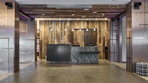 A reception area with a wooden wall backdrop, a marble counter, and a check-in desk.