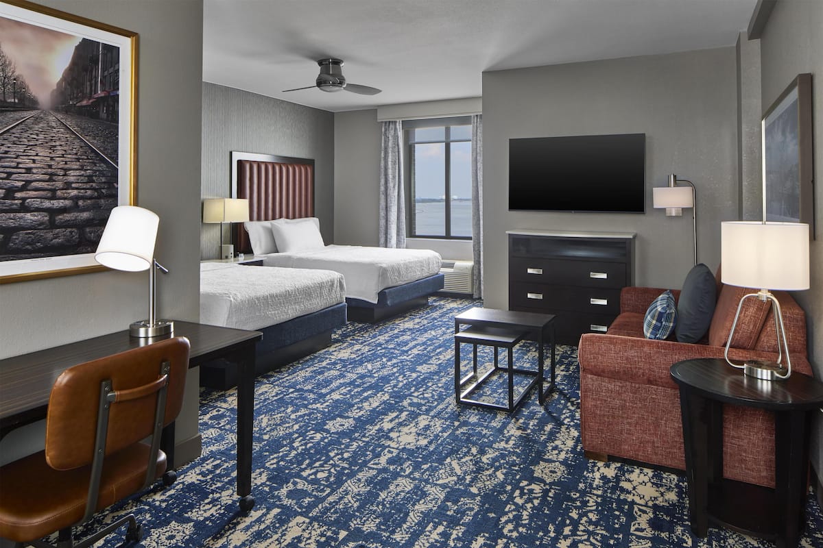 Een hotelkamer met een groot bed, een bureau, een stoel, een bank, een televisie en een raam met uitzicht.