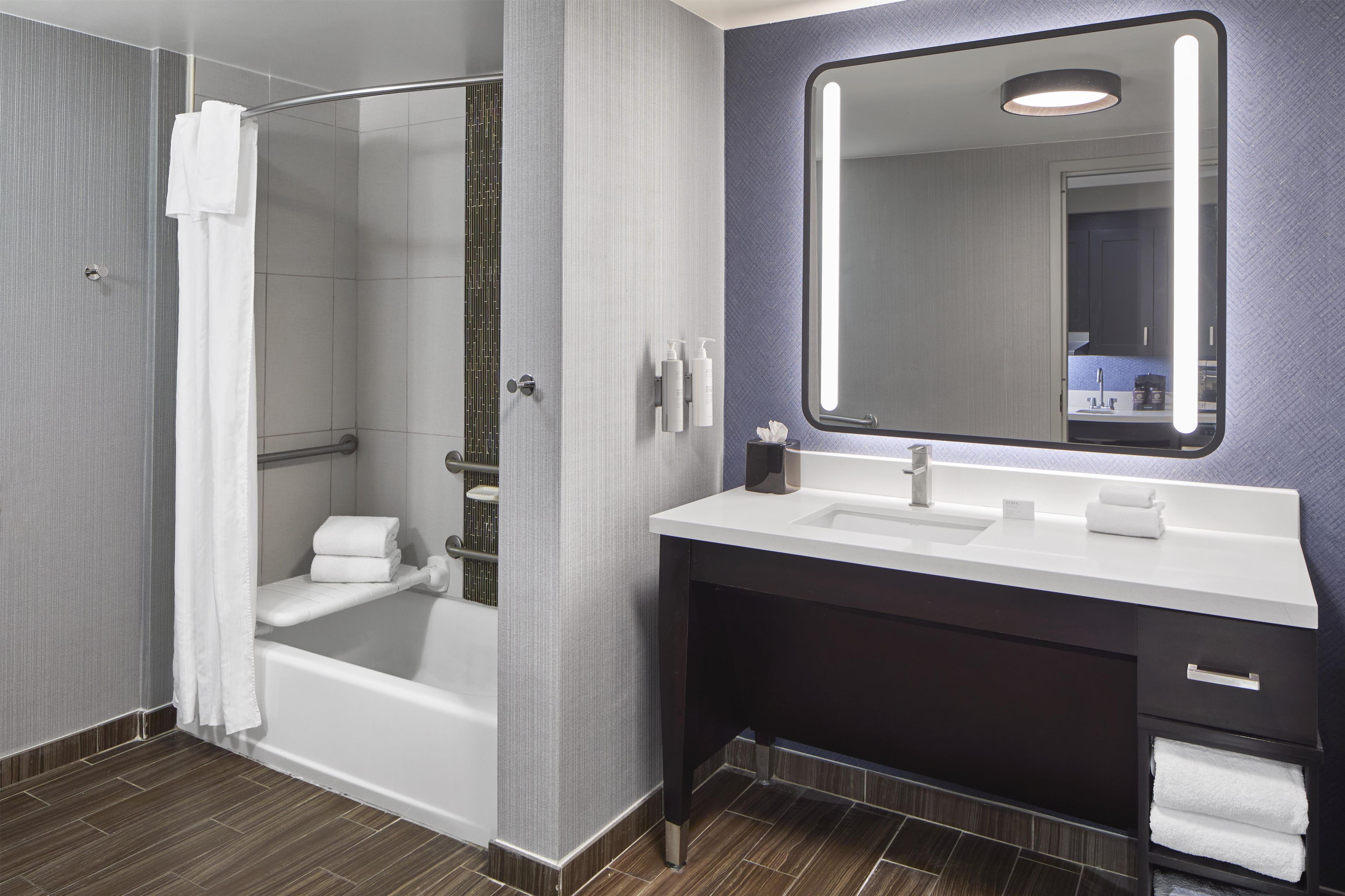 A modern bathroom with a glass-enclosed shower, a vanity with a mirror, and a sink.