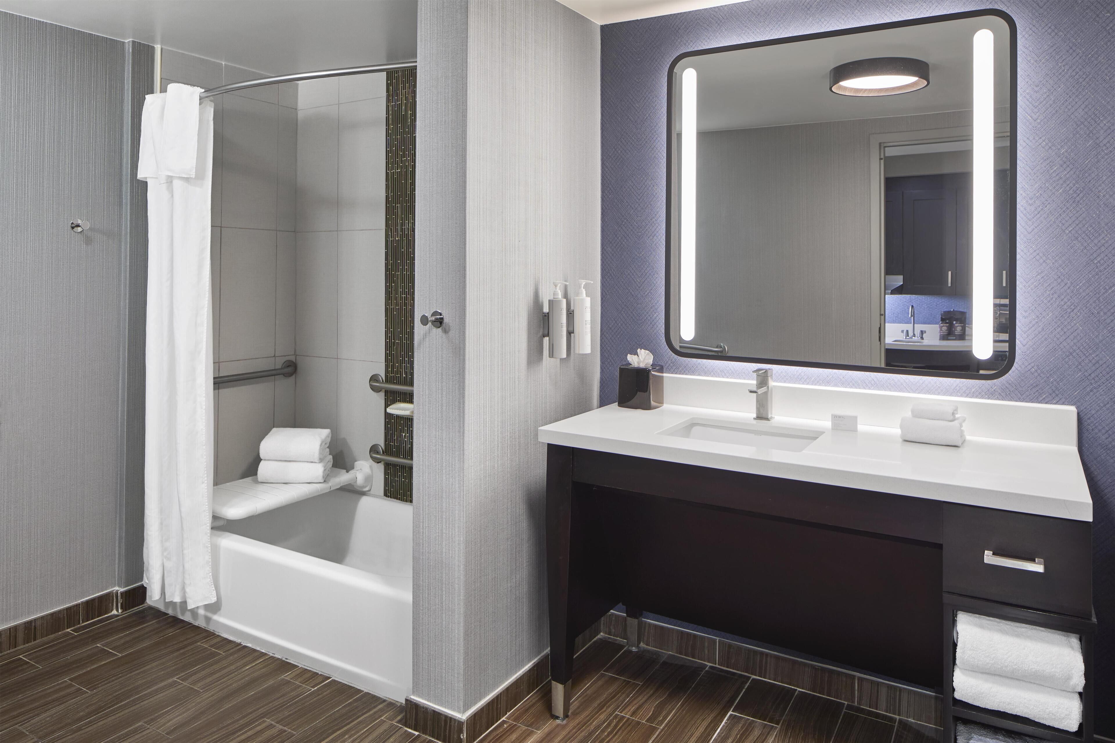 A modern bathroom with a glass-enclosed shower, a vanity with a mirror, and a bathtub.