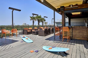 Un espacio al aire libre con mobiliario de mimbre y tablas de surf.