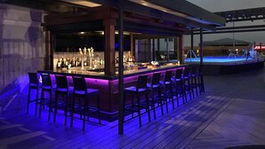 An outdoor bar area with a long counter and multiple bar stools.