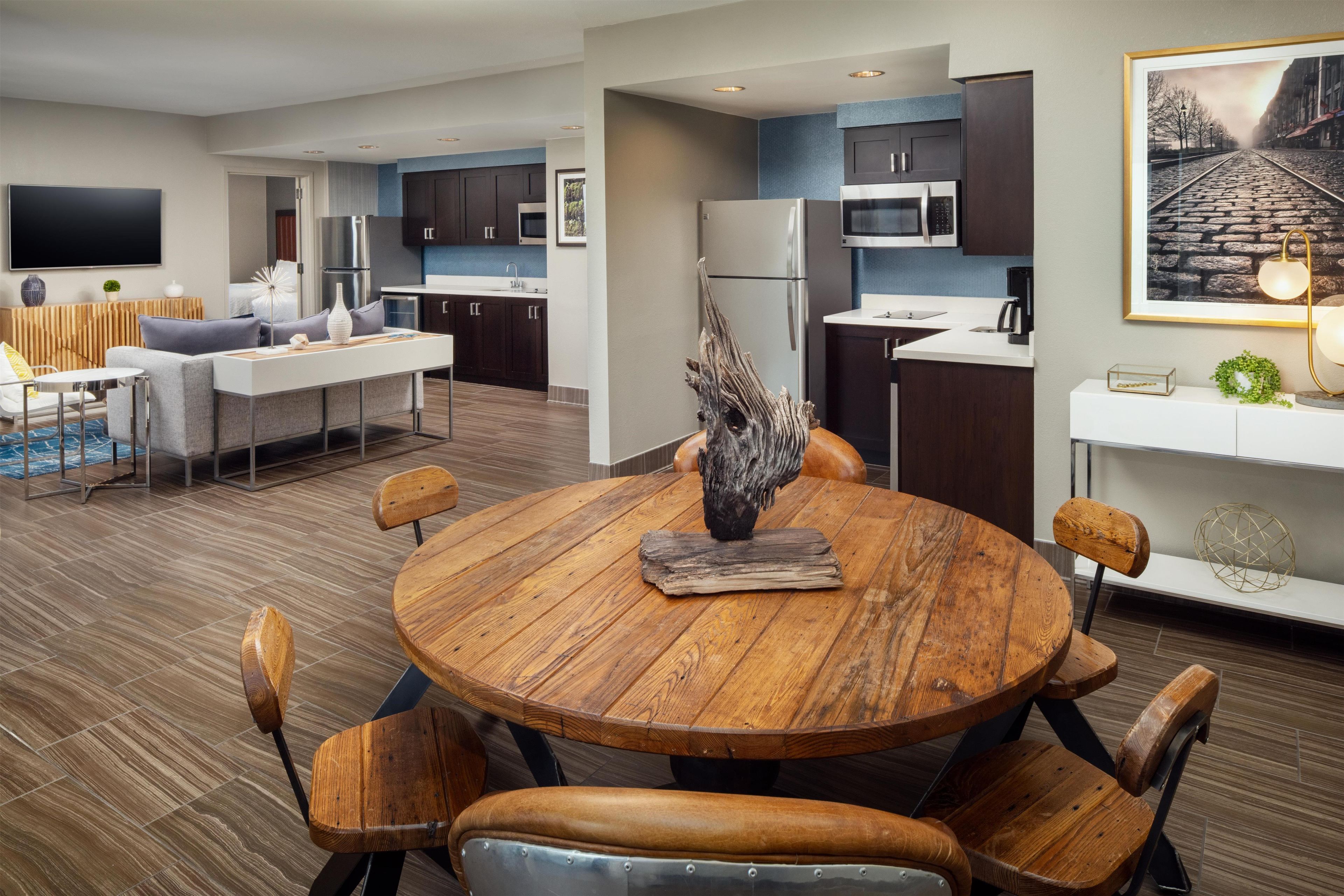 A modern kitchen with dark cabinets, a stainless steel refrigerator, and a microwave.