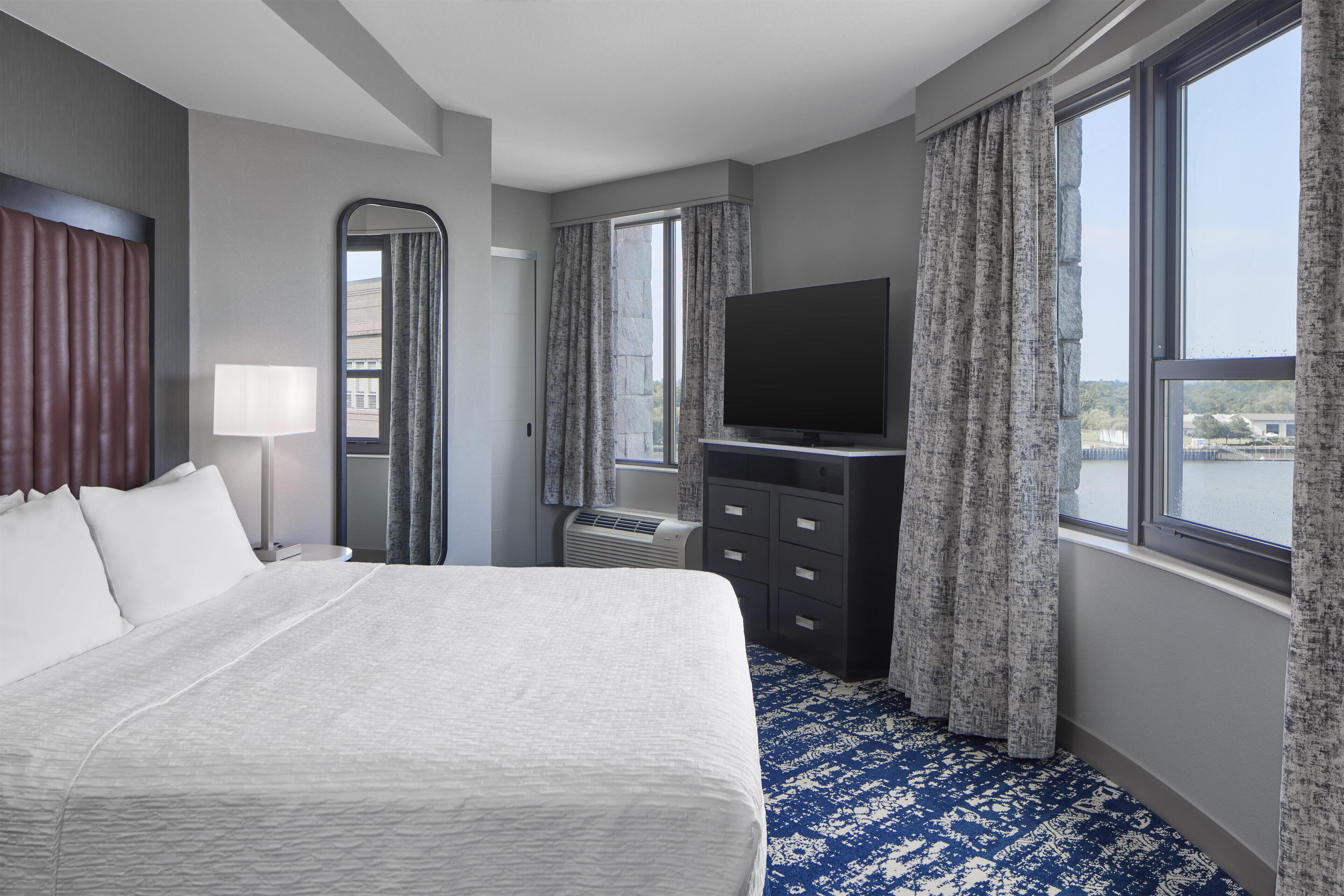 Hotelkamer met een groot bed, een flatscreen televisie, een dressoir en uitzicht op het water.