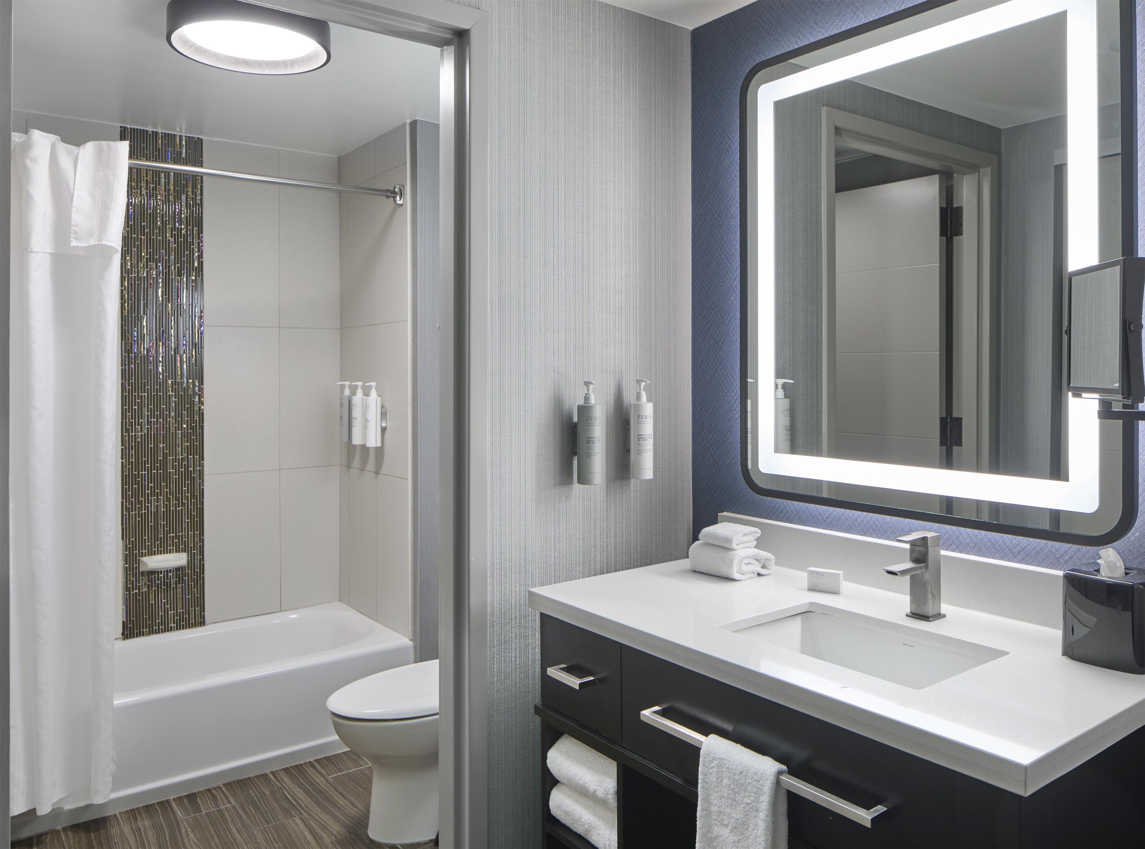 A modern bathroom with a bathtub, toilet, vanity with a mirror, and a shower area.