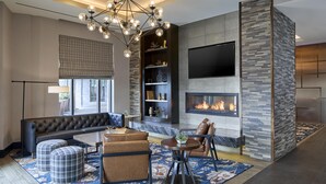 A modern living room with a fireplace, a large TV, and a stylish chandelier.