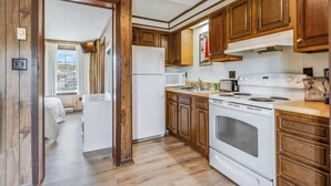 A kitchen with wooden cabinets, a white refrigerator, a stove, and a sink. - The Inn at Lewes (Lewes)