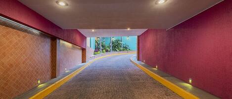 A corridor with red walls, a brick floor, and recessed lighting.