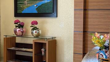 Una sala de estar moderna con un televisor de pantalla plana montado en la pared, una consola de madera con objetos decorativos y una mesa de centro de vidrio.