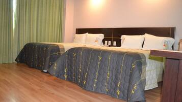 Una habitación de hotel con dos camas, piso de madera y cortina verde.