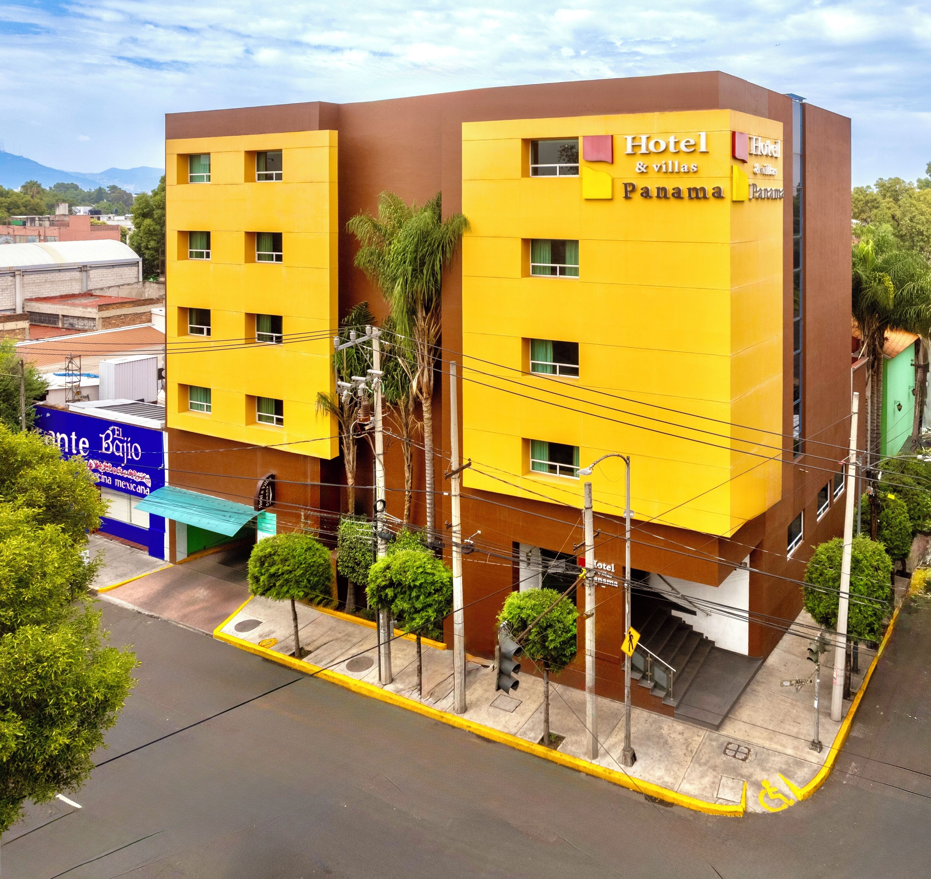 A multi-story hotel with a yellow facade, multiple windows, and a visible entrance.