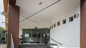 A set of concrete steps leading to a building entrance with a glass door, a metal handrail, and a small sign above the door. - Hotel & Villas Panamá (Mexico City)