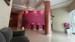 A modern lobby with a red wall, a large pillar, and a framed picture on the wall. - Hotel & Villas Panamá (Mexico City)
