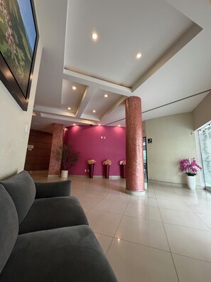 Un hall d’entrée moderne avec un mur rouge, une grande colonne et un tableau encadré accroché au mur.