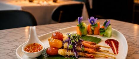 Une assiette de brochettes, accompagnée d’une sauce pour tremper et d’un petit bol de piment.