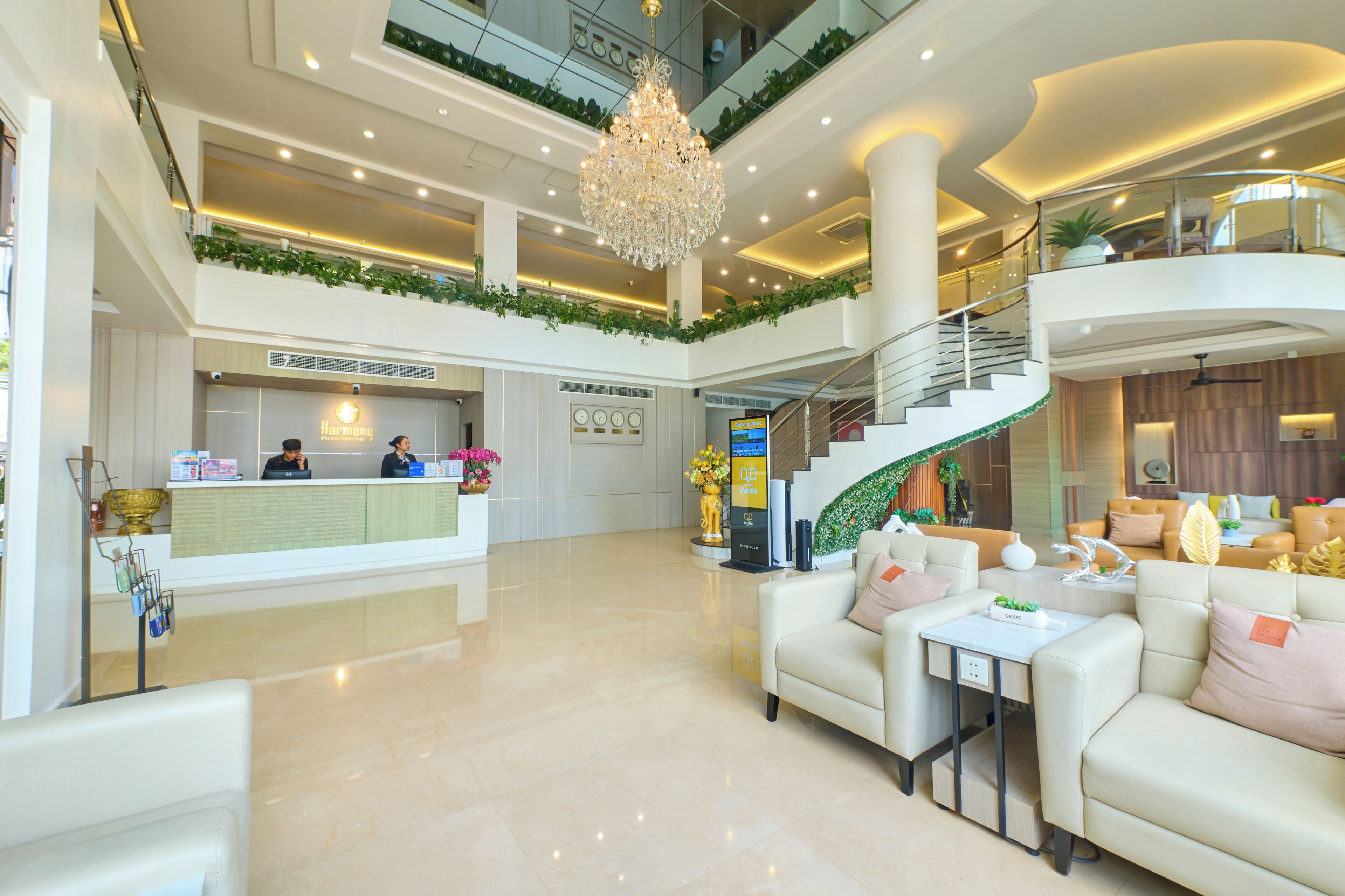 A spacious lobby with a reception desk, a chandelier, a staircase, and seating areas.