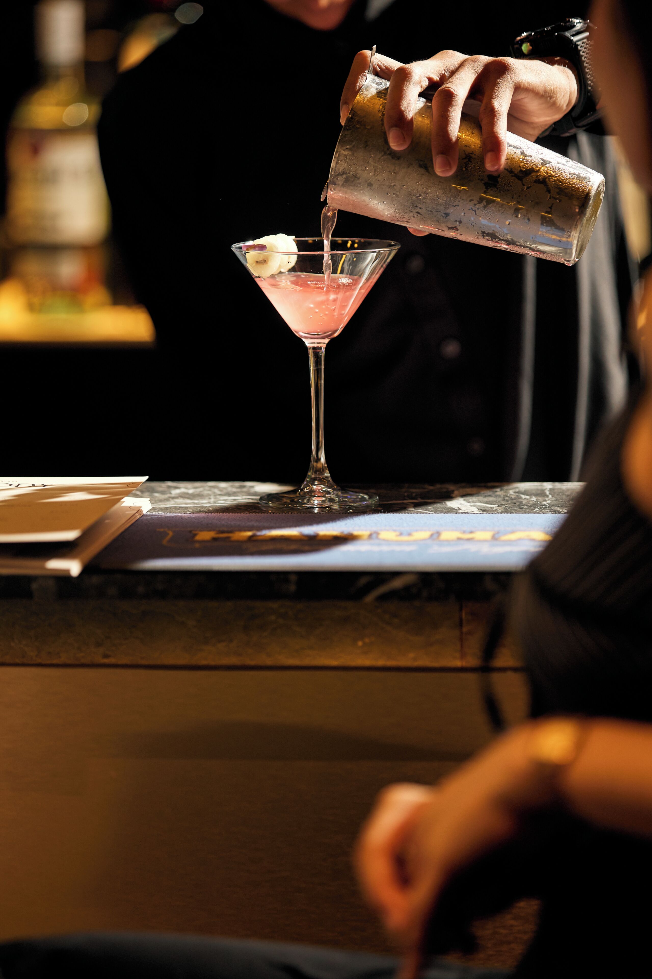 A bartender pouring a drink into a martini glass.