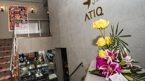 A reception area with a wall-mounted sign reading "ATIQ" and a floral arrangement. - Atiq Boutique Hotel (Cusco)