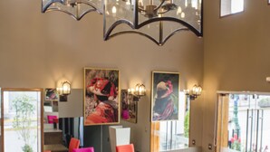A restaurant interior with vibrant orange chairs, wooden tables, and a modern chandelier. - Atiq Boutique Hotel (Cusco)