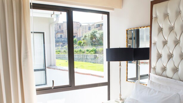 A hotel room with a bed, a tray with breakfast, a window, and a view of the outside. - Atiq Boutique Hotel (Cusco)