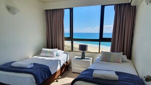 A hotel room with two beds, a nightstand, and a view of the beach. - Princess Palm on the Beach (Palm Beach)