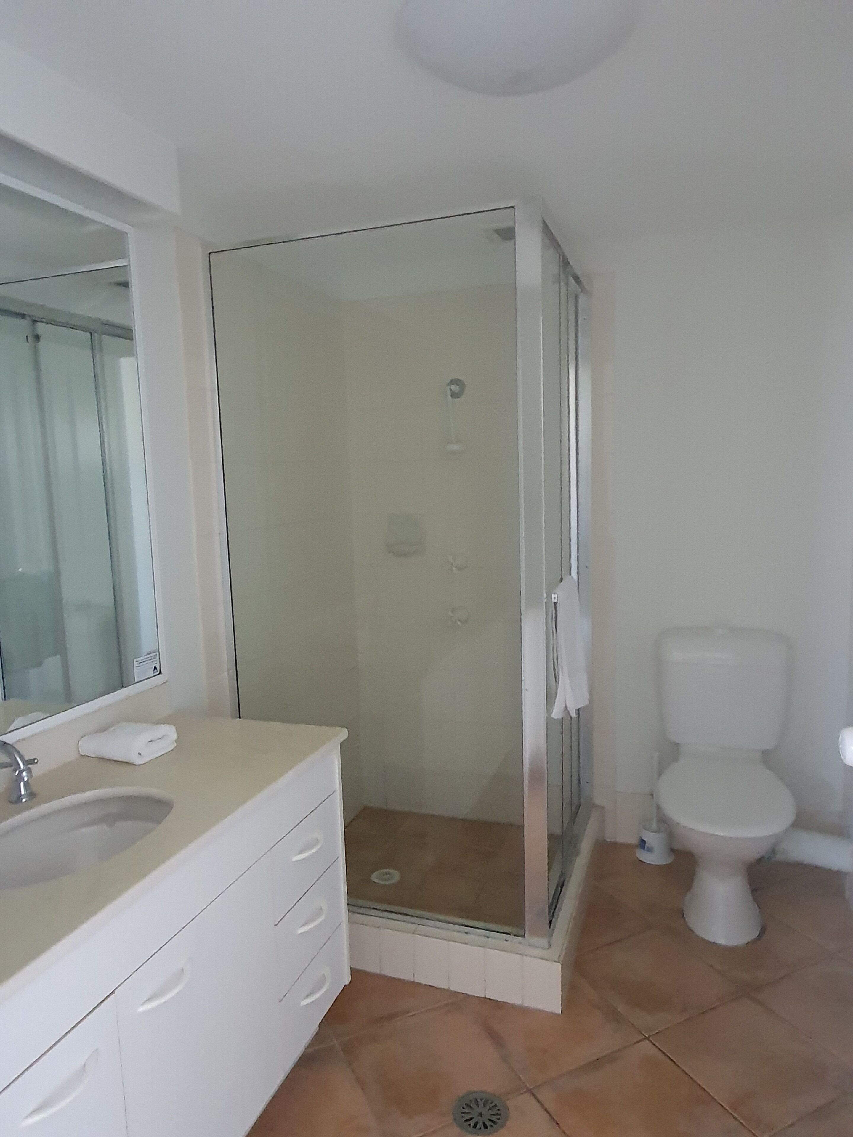 Une salle de bain avec une douche à parois de verre, des toilettes et un lavabo avec un miroir.