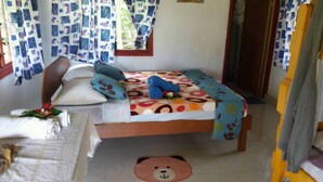 Un dormitorio con cama, almohadas, una mesita de noche, una silla y un tapete con forma de oso en el suelo.