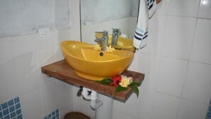 Un lavabo amarillo con un estante de madera, un espejo y una toalla.