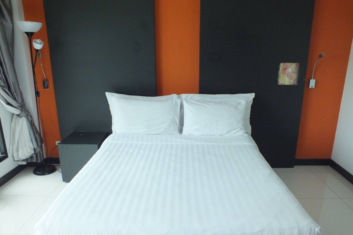 Ein ordentlich gemachtes Bett mit weißen Bettwäsche in einem Hotelzimmer.