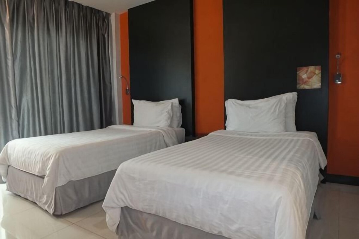 A hotel room with two beds, a large window with curtains, and a modern wall design.