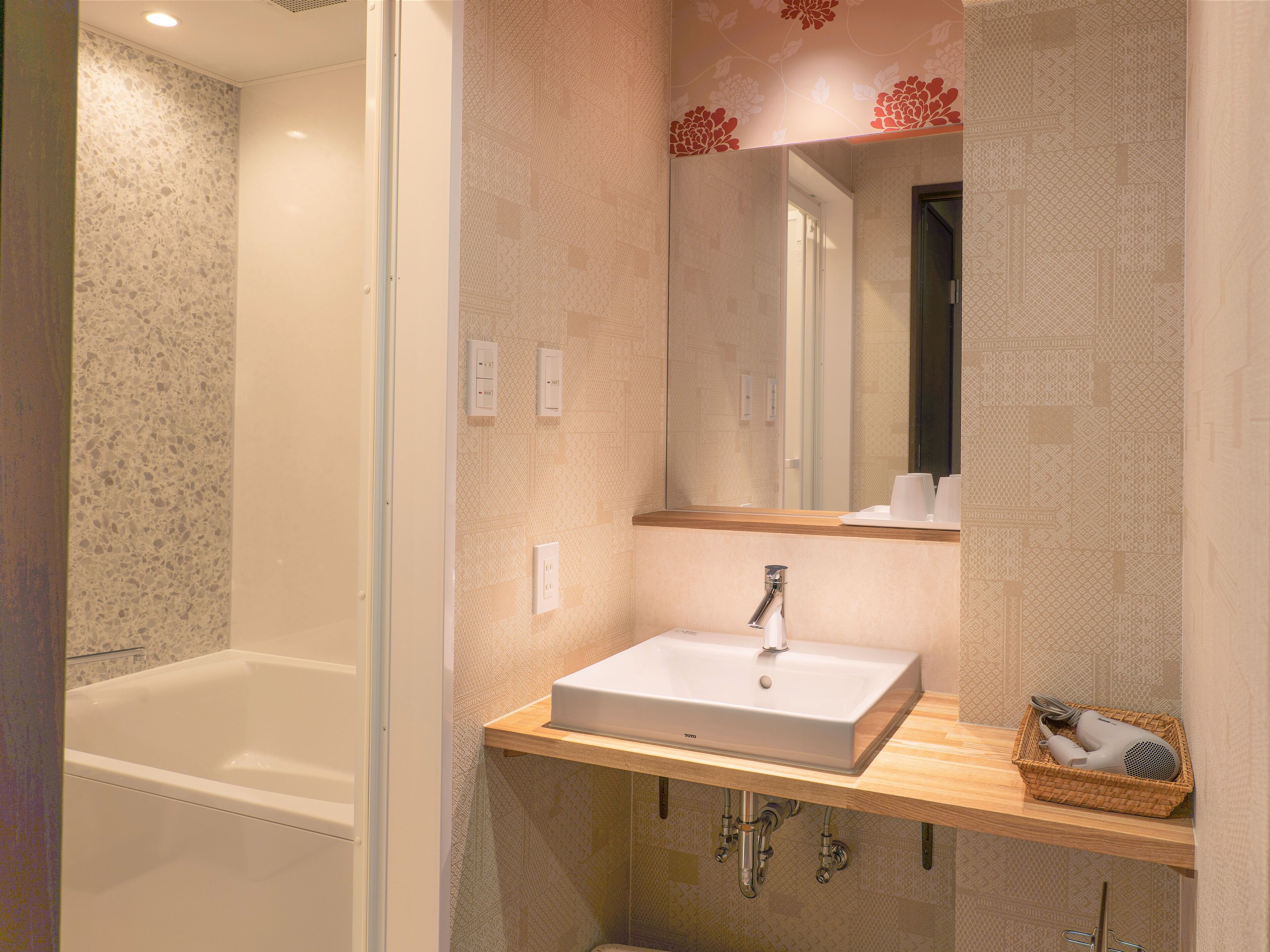 A bathroom with a bathtub, a sink with a mirror, and a shelf with toiletries.