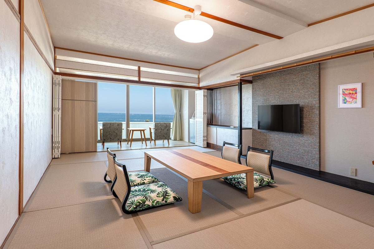Una stanza con pavimento in tatami, un tavolo di legno e sedie con cuscini a motivi floreali.
