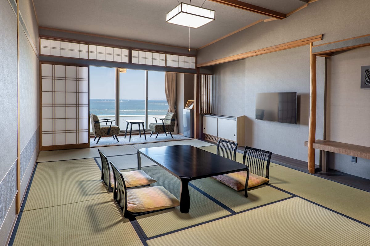 Una tradizionale stanza giapponese con pavimento in tatami, un tavolino e vista sul mare.