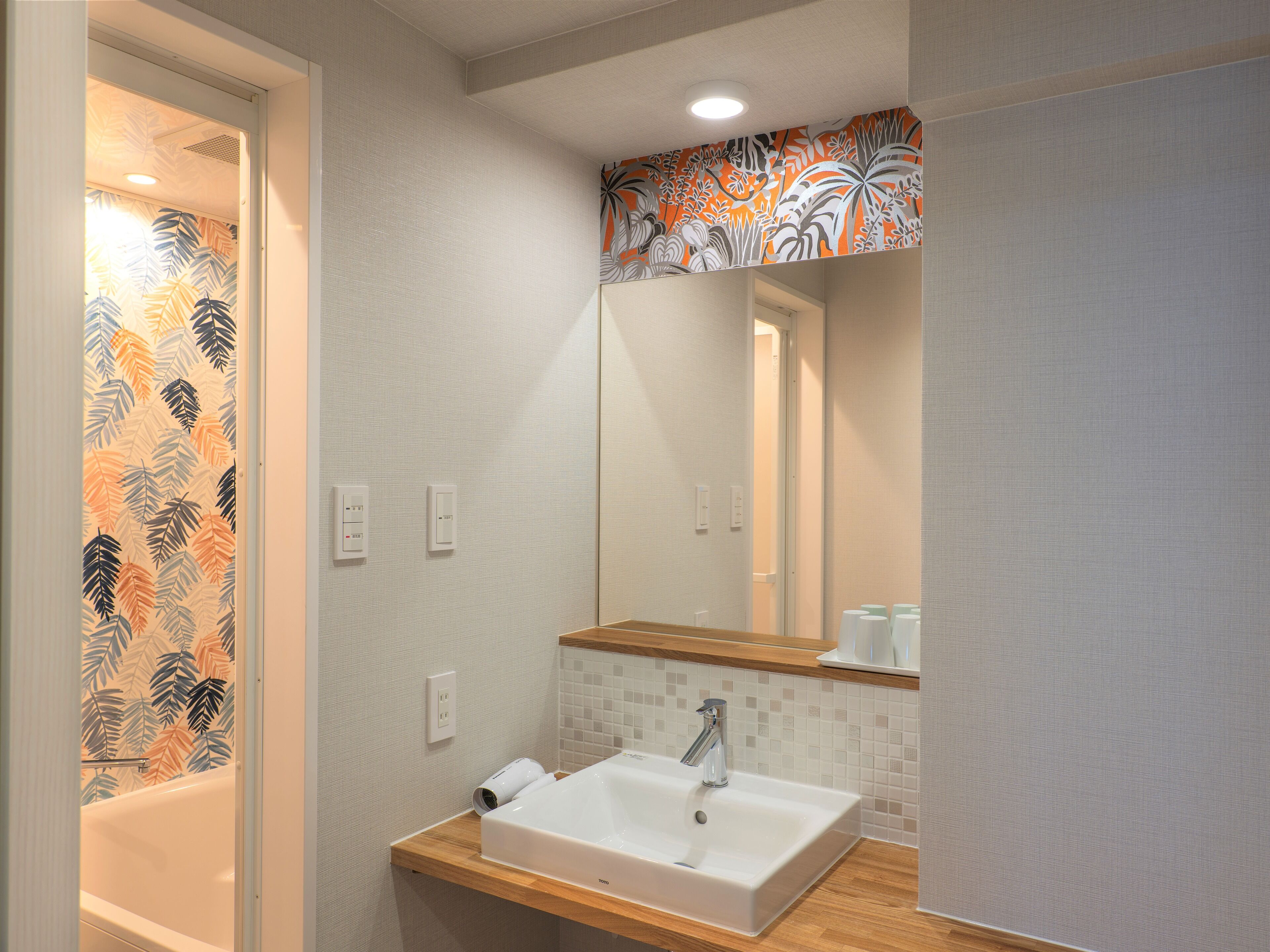 A modern bathroom with a white sink, a mirror, and a shower.