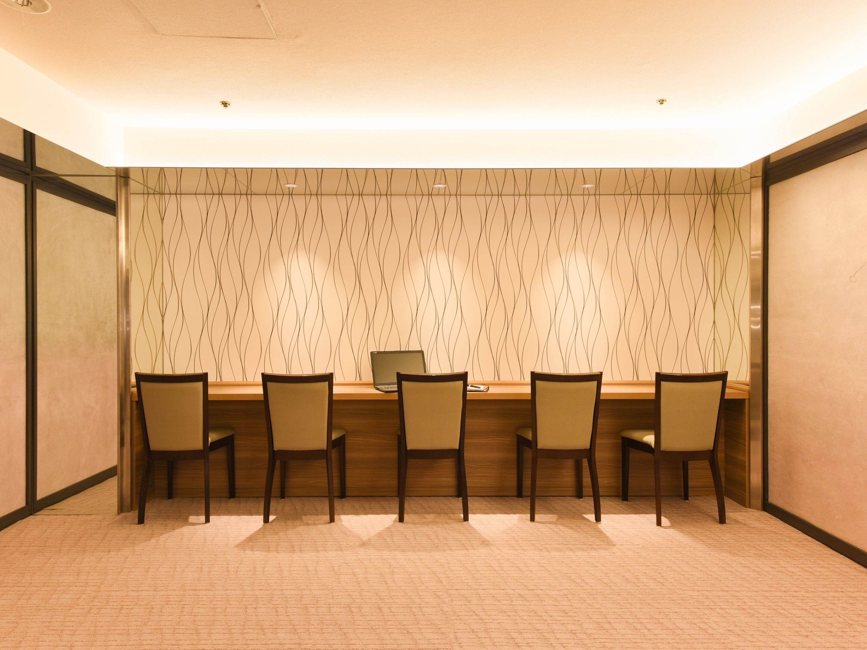A conference room with a long table, five chairs, and a laptop on the table.