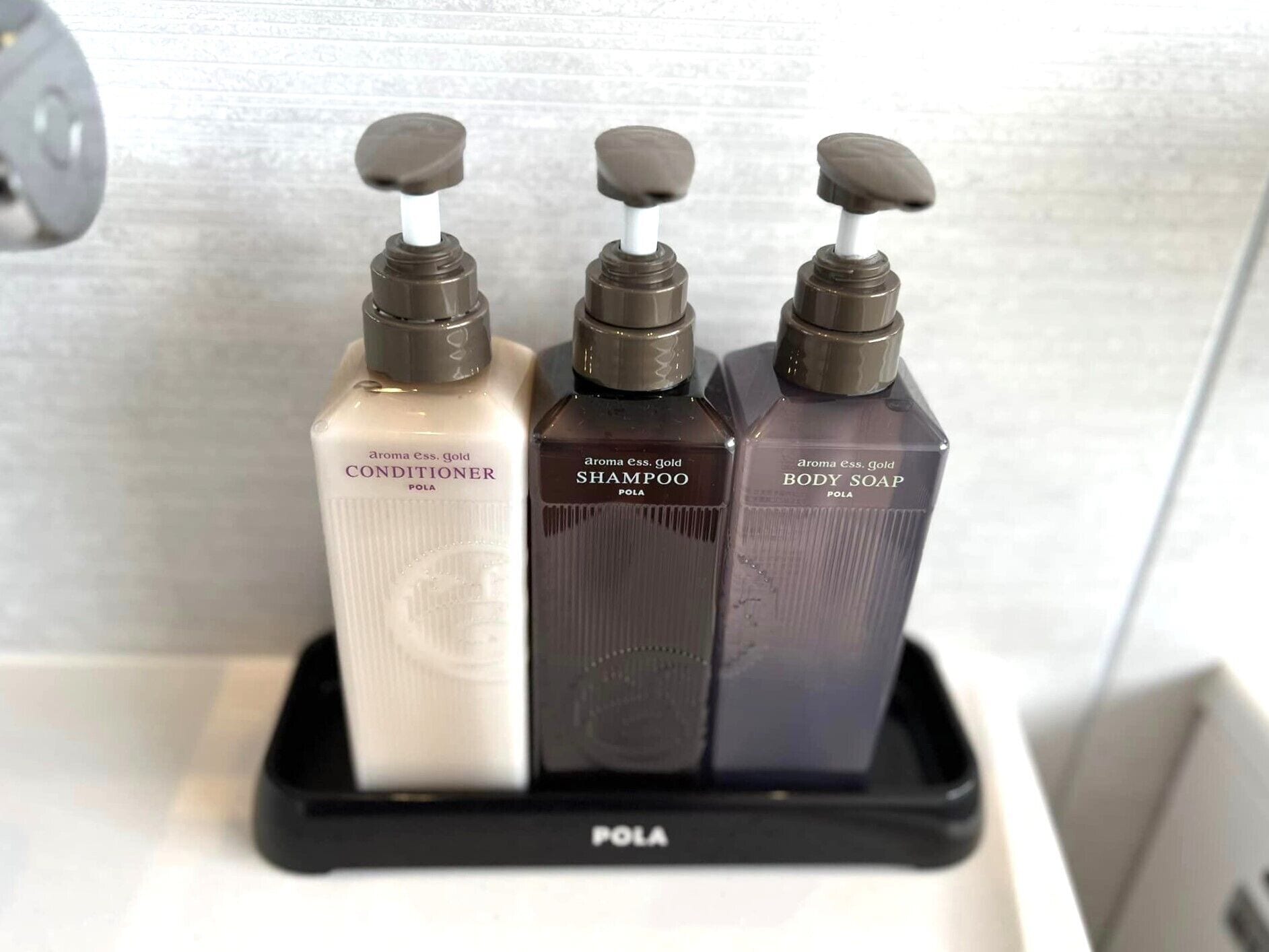 Three bottles of POLA products: conditioner, shampoo, and body soap.