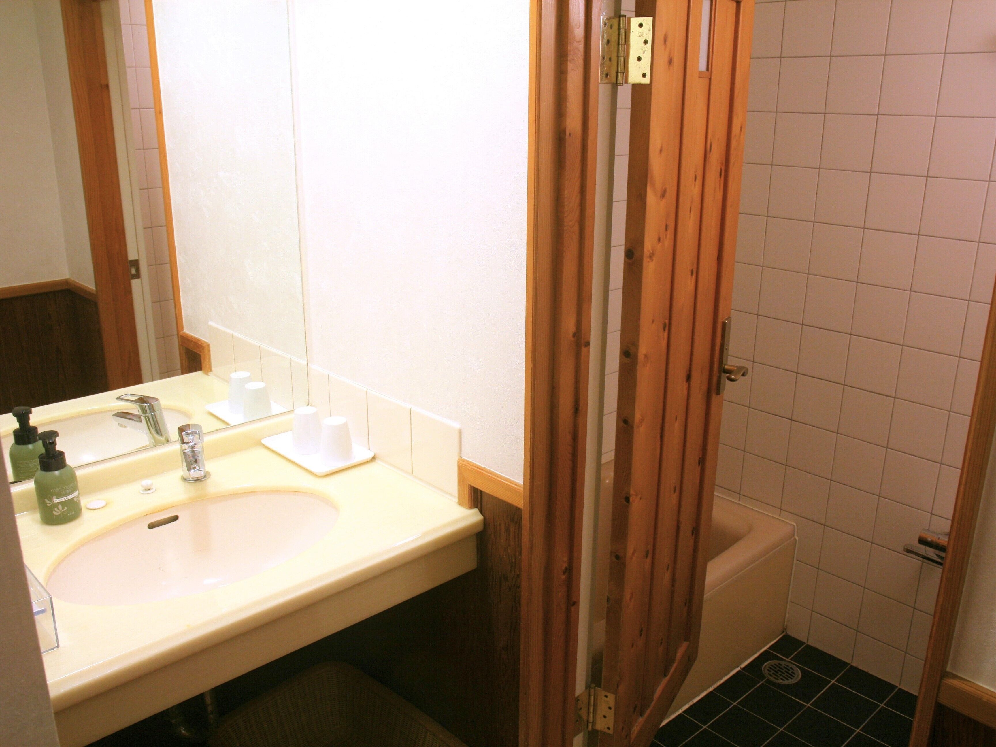 A bathroom with a sink, mirror, and wooden door.