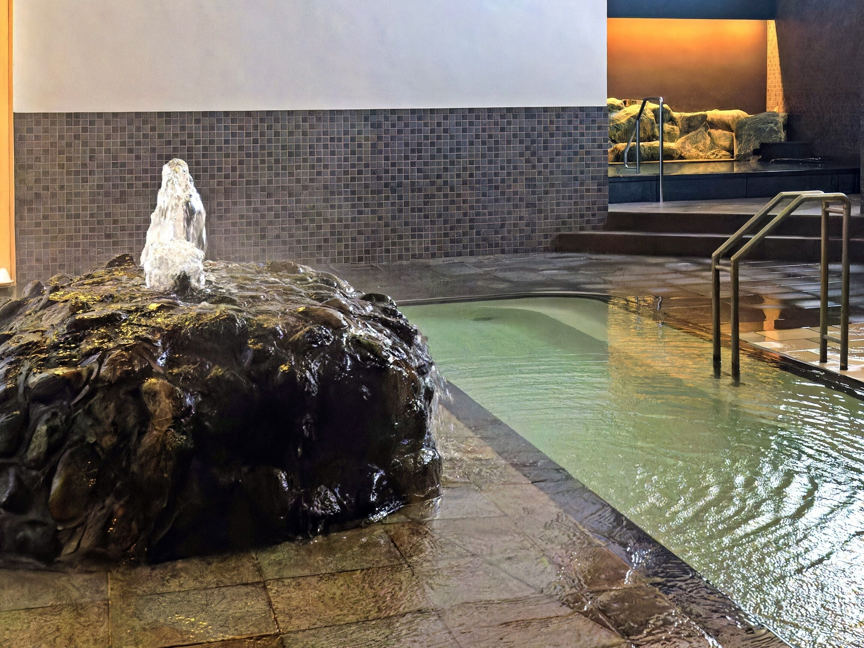 A pool area with a rock feature and a staircase leading to a higher level.