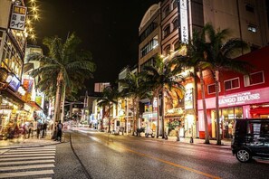Una calle bordeada de palmeras y comercios, incluyendo Mango House.