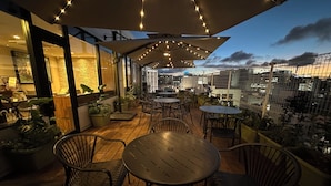 An outdoor seating area with tables and chairs, string lights, and potted plants. - Hotel Naha City -Kokusai Street- (Naha)