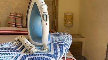 Un fer à repasser posé sur une nappe à motifs, avec un lit en arrière-plan.
