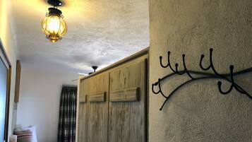 A bedroom with a bed, a wardrobe, a wall-mounted light fixture, and a decorative wall piece.