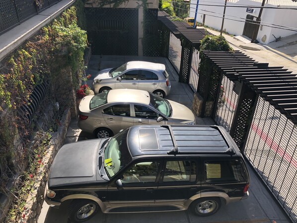 A narrow street with parked cars and a black SUV.