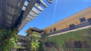 Une cour intérieure avec un mur en pierre, des plantes et un bâtiment doté d’un toit en tuiles.